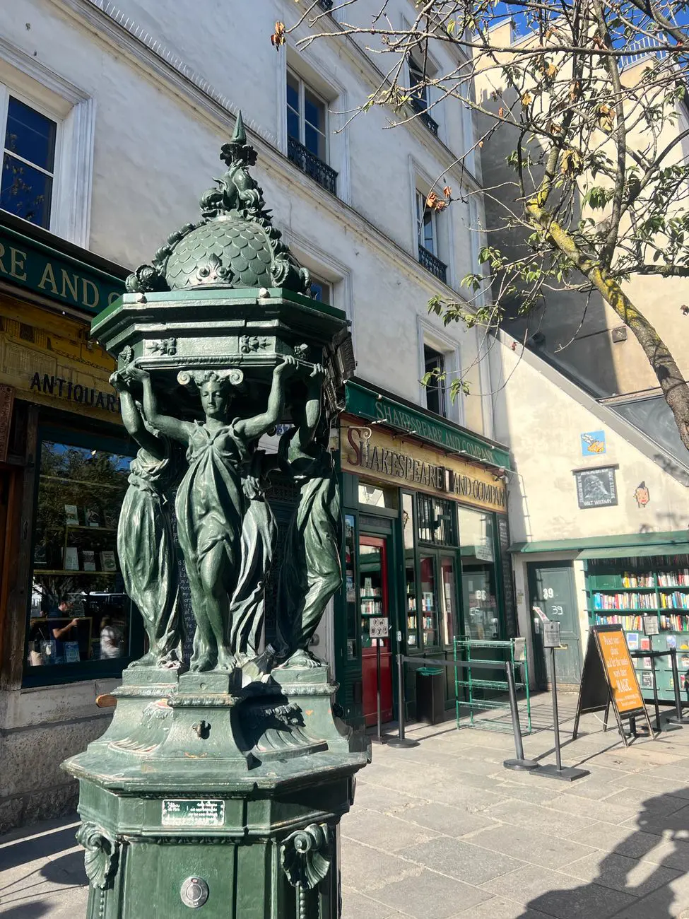 A green Wallace fountain outside Shakespeare and Company. Drinking water, free.